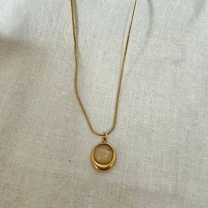 Gold necklace with a round pendant on a light fabric background